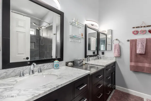 a bathroom with a granite countertop double vanity sink and a mirror