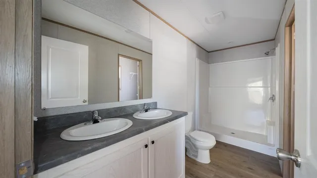 a bathroom with a granite countertop sink toilet a mirror and shower
