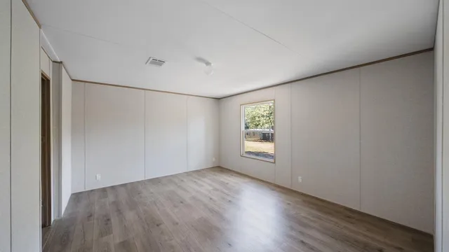 a view of an empty room with a window and wooden floor