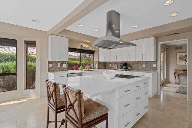 a kitchen with stainless steel appliances kitchen island a table chairs sink and cabinets