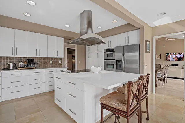 a kitchen with stainless steel appliances kitchen island granite countertop a refrigerator and a stove top oven