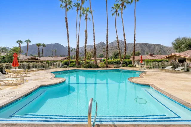 a view of a swimming pool with a lawn chairs under an umbrella
