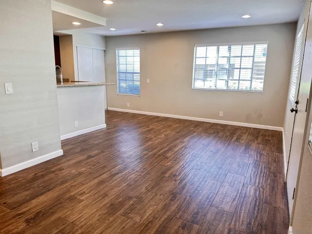 an empty room with wooden floor and windows