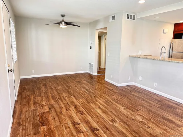 a view of a room with wooden floor and a ceiling fan