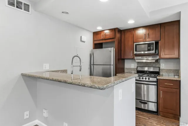 a kitchen with kitchen island granite countertop stainless steel appliances and refrigerator