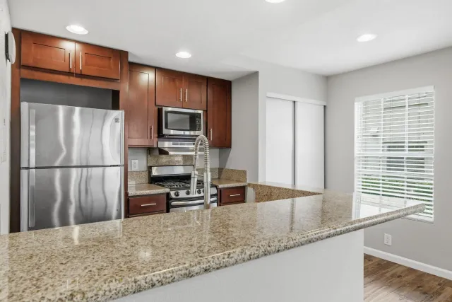 a kitchen with granite countertop a refrigerator and a sink