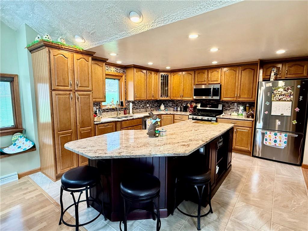 198 Leslie Road Valencia, PA 16059 - Photo 14 of 43 a kitchen with stainless steel appliances granite countertop a table chairs and a refrigerator