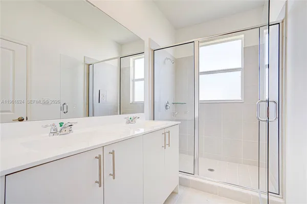 a view of bathroom with a sink mirror and shower