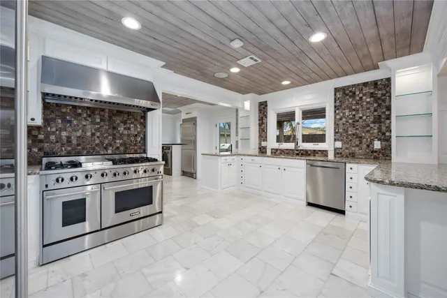a kitchen with stainless steel appliances a stove top oven a refrigerator and a sink