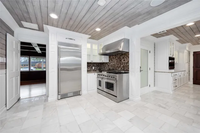 a large white kitchen with granite countertop a sink and dishwasher a stove with white cabinets