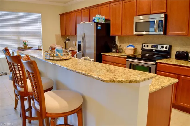 a kitchen with stainless steel appliances granite countertop a sink a stove a refrigerator a dining table and chairs