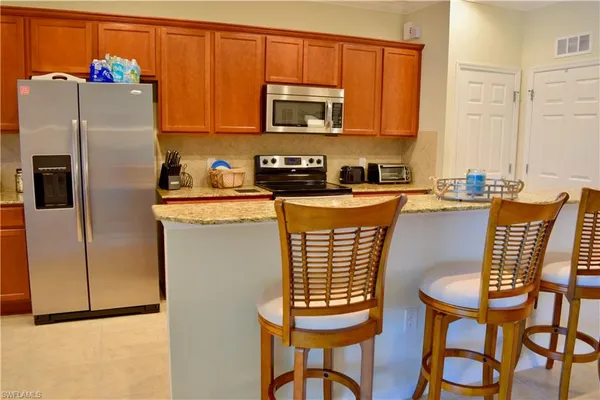 a kitchen with stainless steel appliances granite countertop a refrigerator a stove a sink dishwasher with a dining table and chairs
