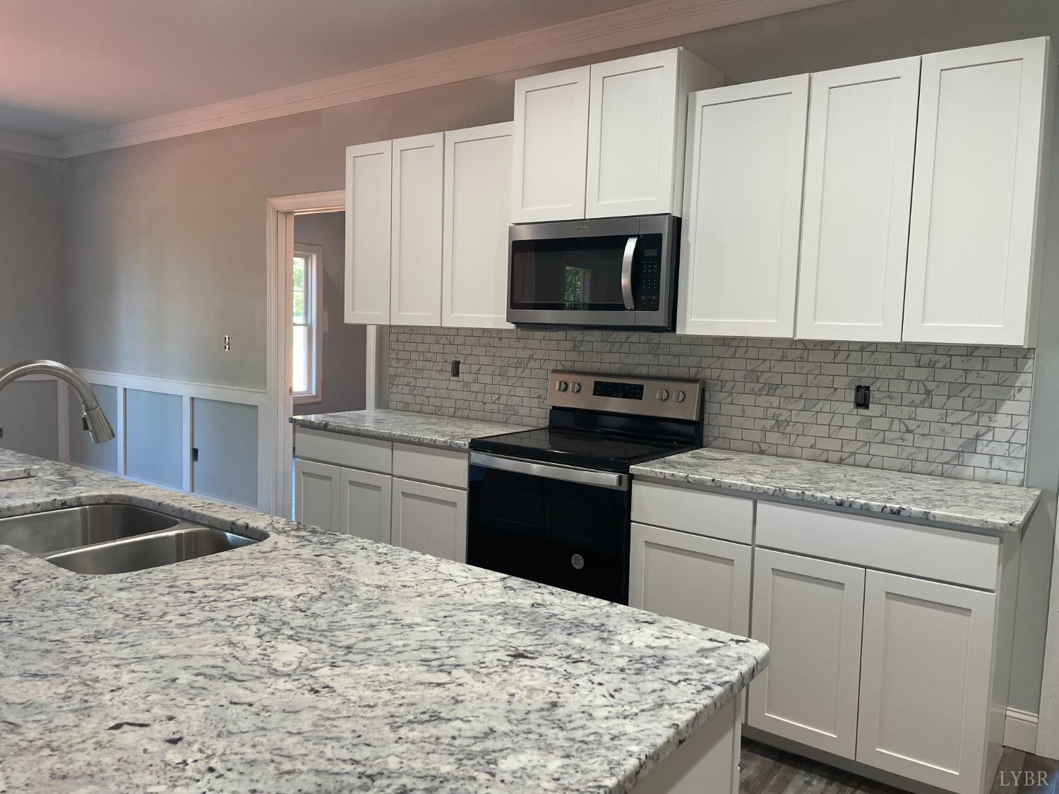 1075 Everett Road Forest, VA 24551 - Photo 6 of 12 a kitchen with kitchen island granite countertop a sink stainless steel appliances and white cabinets