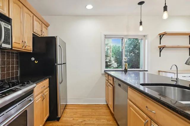a kitchen with stainless steel appliances granite countertop a sink a stove and a refrigerator
