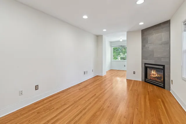 a view of empty room with wooden floor and fireplace
