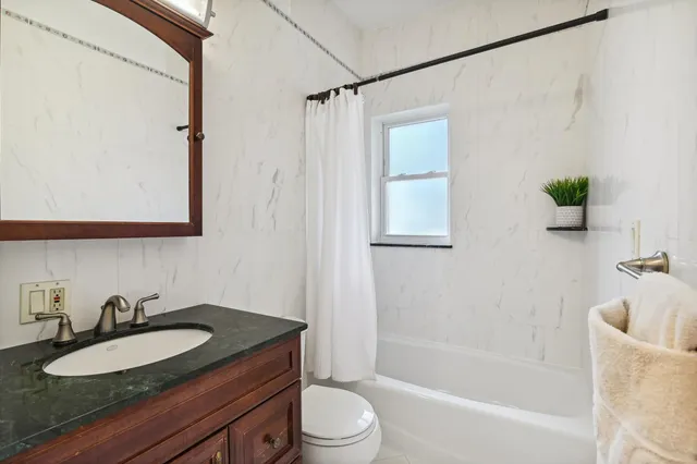 a bathroom with a granite countertop sink mirror vanity and toilet