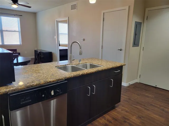 a kitchen with granite countertop a sink cabinets and wooden floor