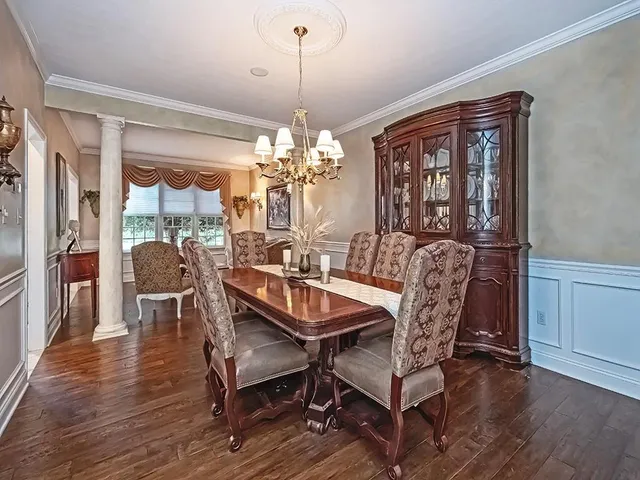 a dining room with furniture wooden floor a rug a potted plant and a chandelier