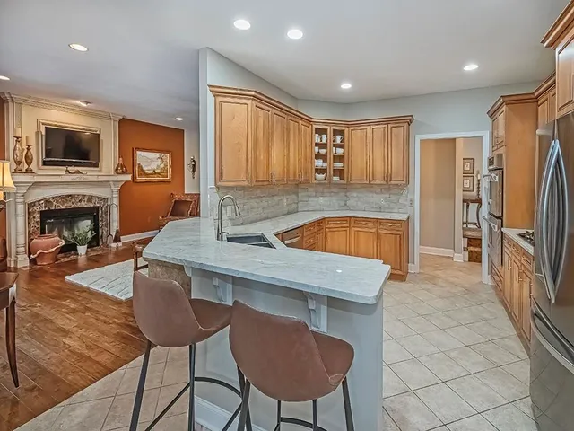 a kitchen with stainless steel appliances granite countertop a refrigerator a stove a sink a dining table and chairs with wooden floor