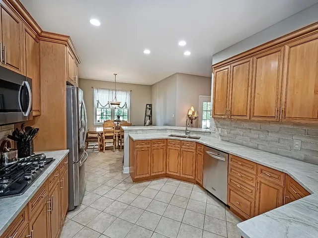 a kitchen with stainless steel appliances granite countertop sink stove top oven refrigerator and cabinets