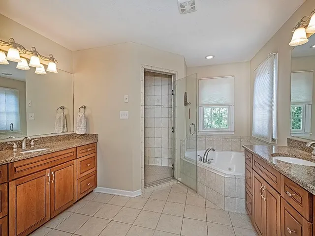 a spacious bathroom with a granite countertop tub sink a mirror a shower and vanity