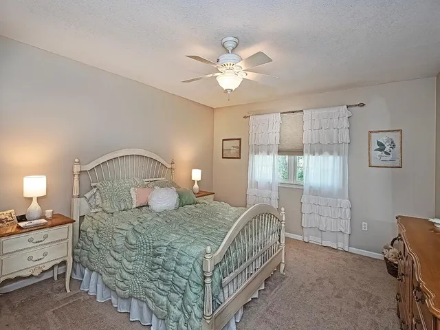 a bedroom with a bed a chandelier and dresser