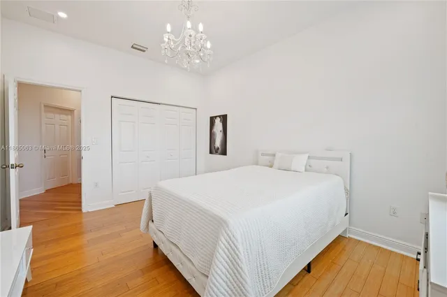 a spacious bedroom with a bed and wooden floor
