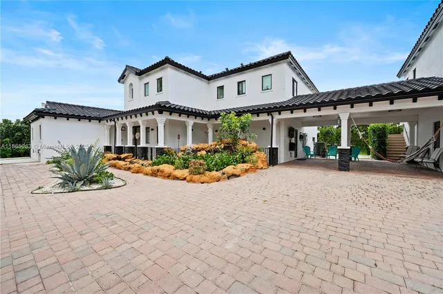 a view of a white house with a large space and a car park in front of it