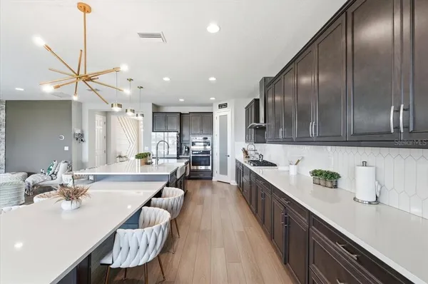 a large kitchen with kitchen island a large counter top space a sink stainless steel appliances and cabinets