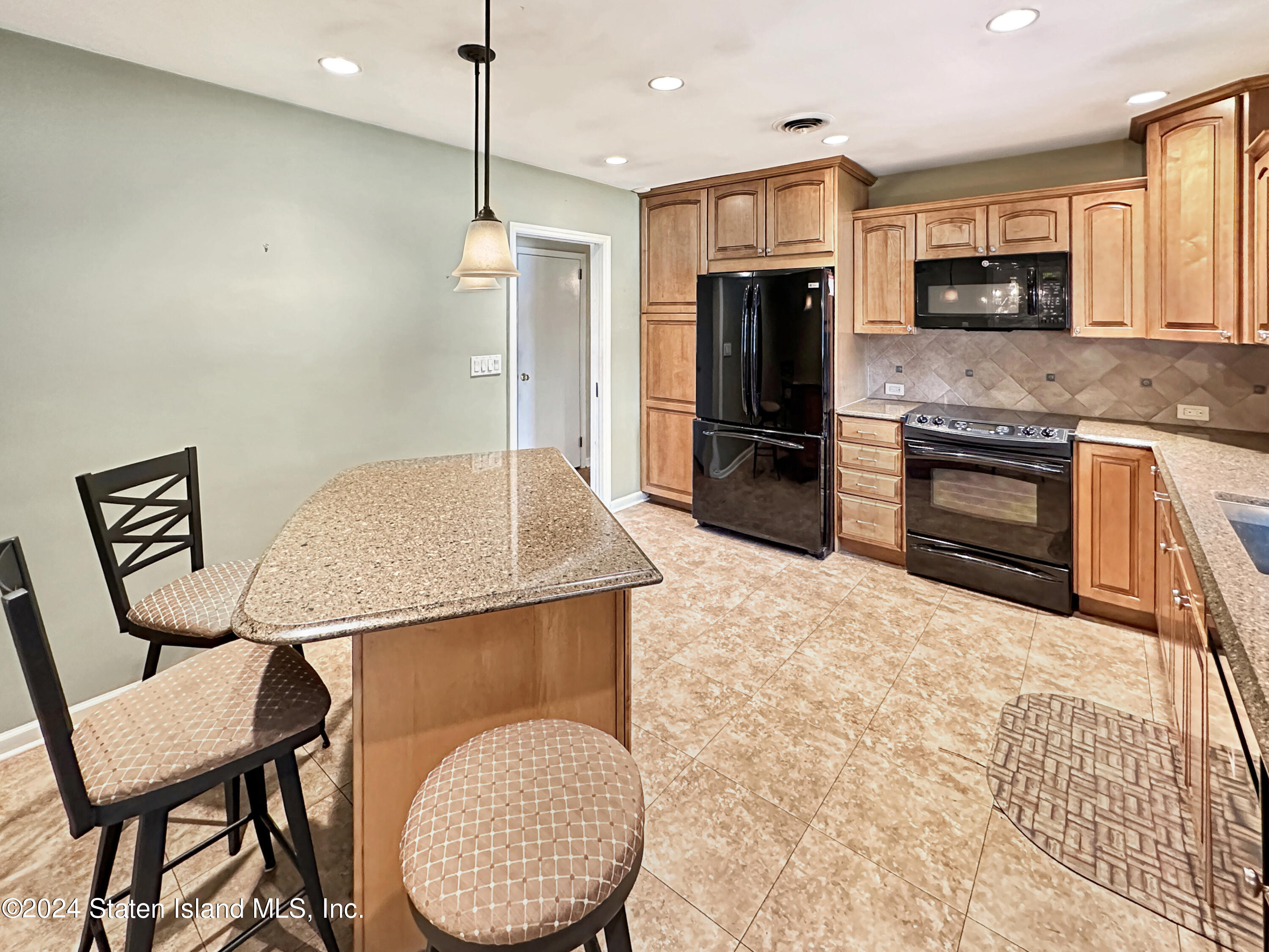1085 Todt Hill Road Staten Island, NY 10304 - Photo 3 of 14 a kitchen with stainless steel appliances granite countertop a stove a refrigerator a kitchen island a sink dishwasher a dining table and chairs with wooden floor