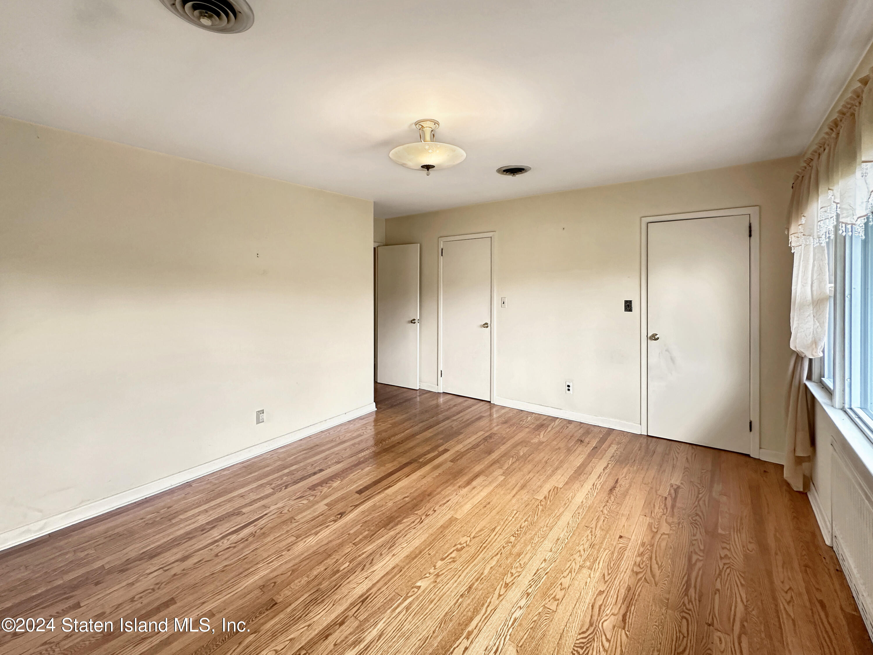 1085 Todt Hill Road Staten Island, NY 10304 - Photo 5 of 14 wooden floor in an empty room with a window