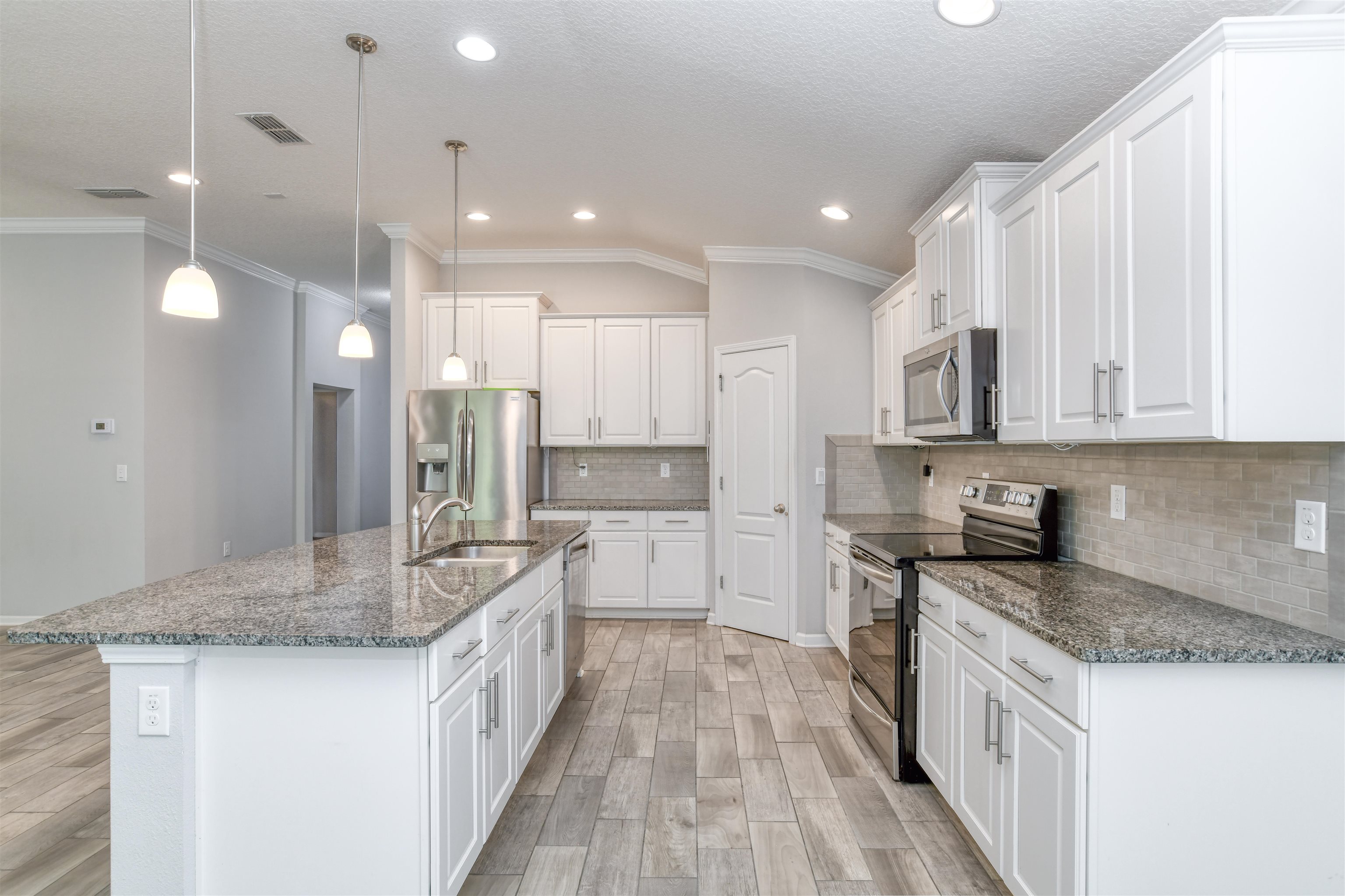 485 Crescent Key Drive St. Augustine, FL 32086 - Photo 10 of 46 a kitchen with kitchen island granite countertop wooden cabinets and white appliances