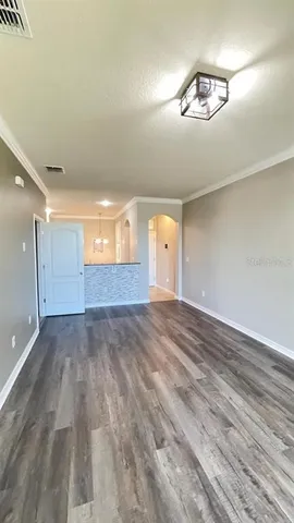 an empty room with wooden floor and chandelier