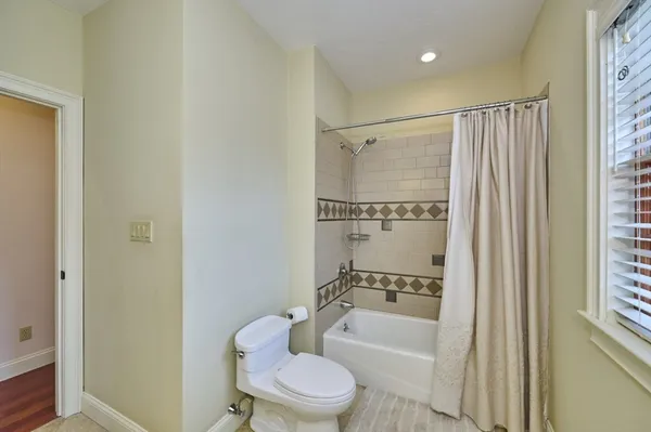 a bathroom with a granite countertop bathtub shower sink vanity and toilet