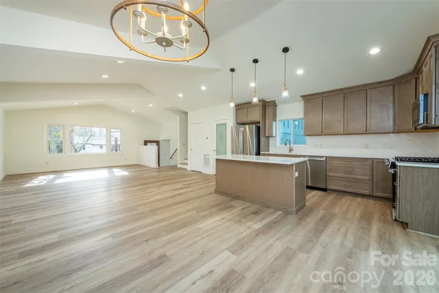 a large kitchen with stainless steel appliances kitchen island a large counter top and a wooden floors