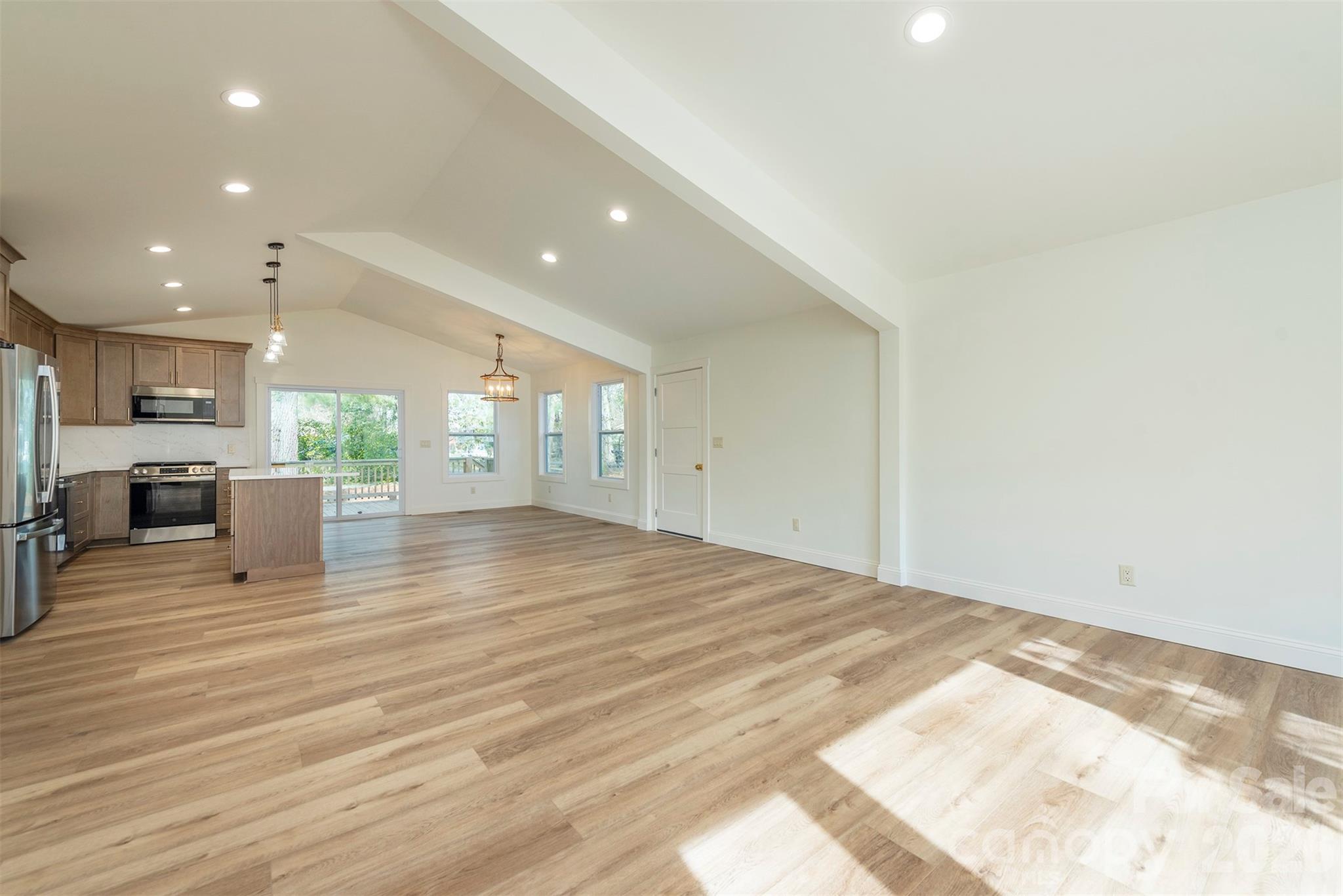 524 Pineland Road Hendersonville, NC 28792 - Photo 14 of 36 a view of an empty room with wooden floor and a kitchen
