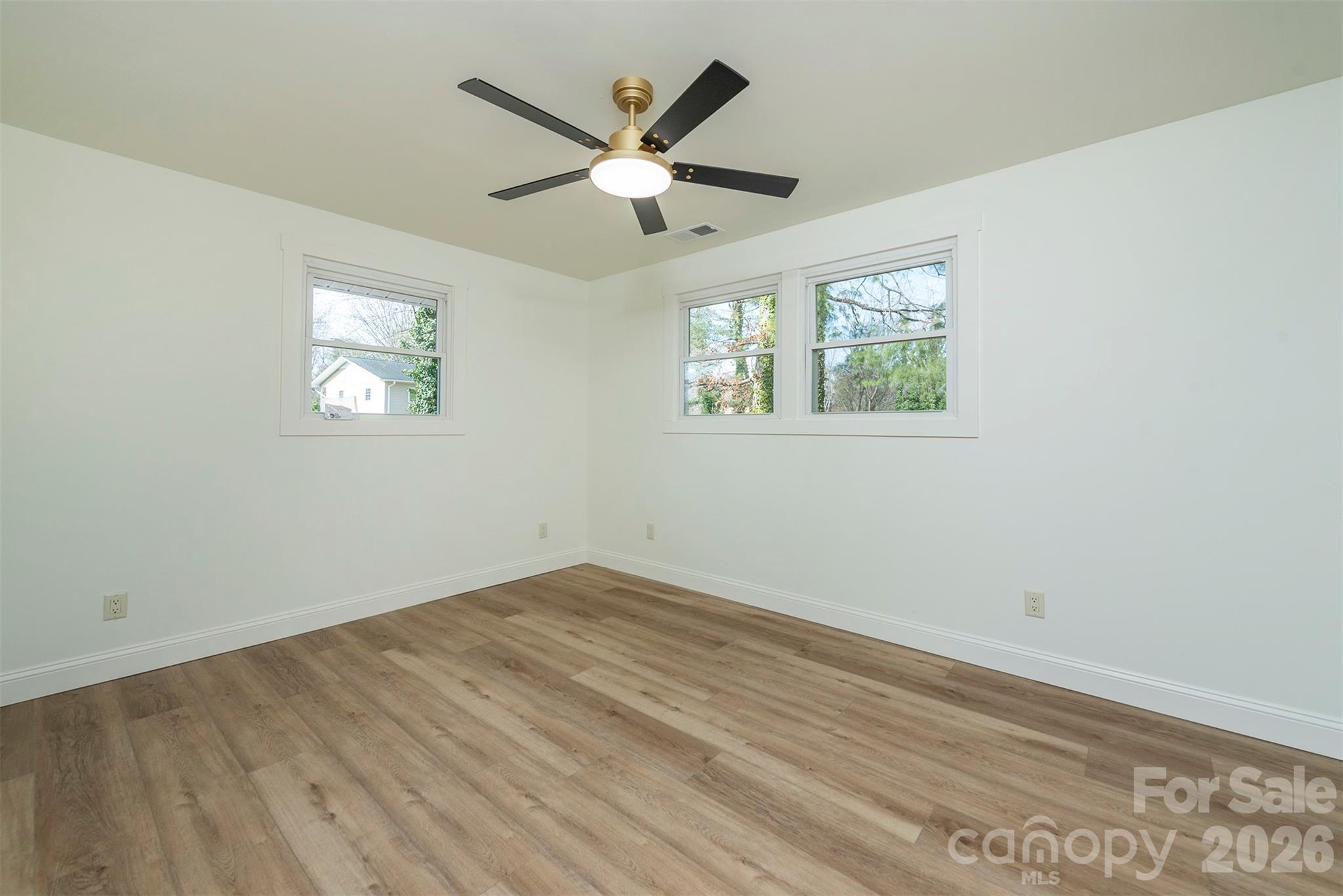 524 Pineland Road Hendersonville, NC 28792 - Photo 20 of 36 an empty room with wooden floor ceiling fan and windows