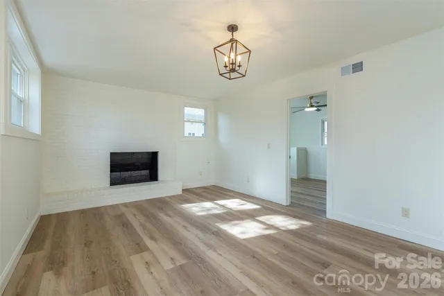 a view of empty room with wooden floor and fireplace