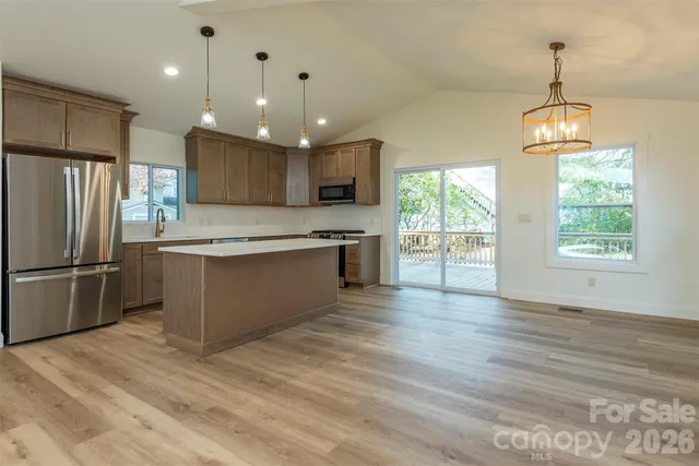 a kitchen with stainless steel appliances granite countertop a refrigerator a sink dishwasher a stove and a refrigerator with wooden floor