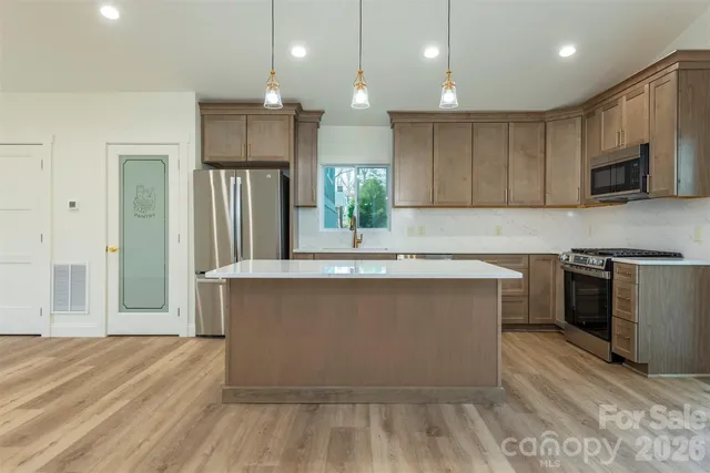 a kitchen with kitchen island a counter top stainless steel appliances and cabinets