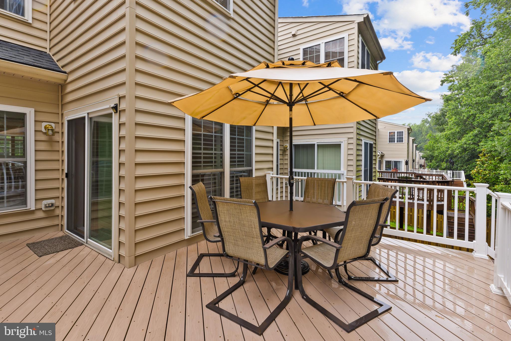 2433 Killarney Terrace Odenton, MD 21113 - Photo 16 of 48 a view of a roof deck with table and chairs under an umbrella with wooden floor