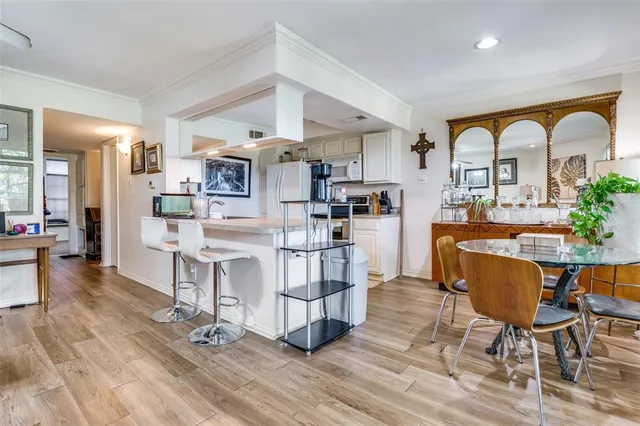 a living room with couches a dining table chairs and kitchen view with wooden floor