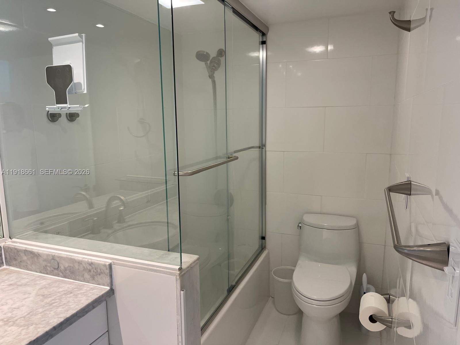 16909 North Bay Road, Unit 716 Sunny Isles Beach, FL 33160 - Photo 18 of 26 a bathroom with a granite countertop toilet a sink and shower