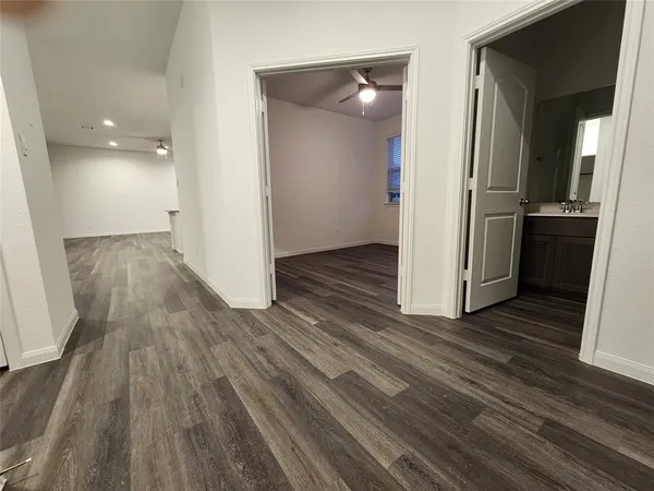an empty room with wooden floor and a kitchen