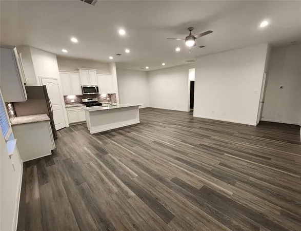 a large white kitchen with wooden floors and a fireplace