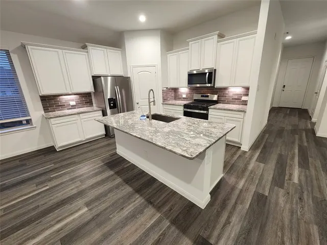 a kitchen with a refrigerator stove and wooden floor