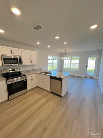 a large kitchen with stainless steel appliances granite countertop a stove a sink dishwasher and a oven with white cabinets