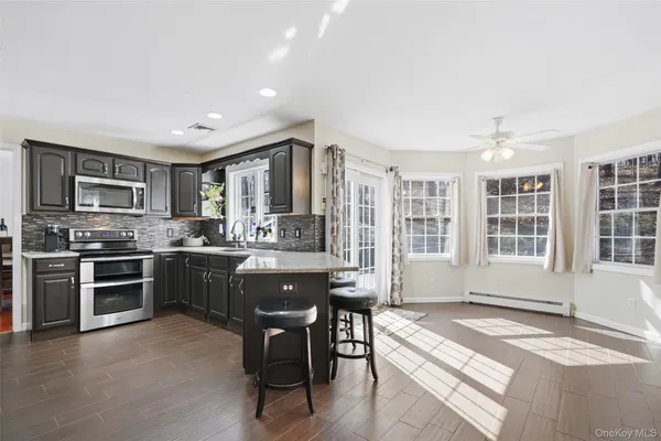 a kitchen with stainless steel appliances granite countertop a stove top oven a sink dishwasher a dining table and chairs with wooden floor