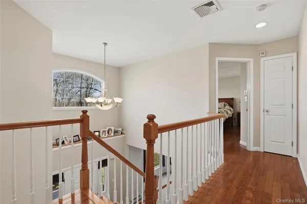 a view of a hallway to a livingroom with wooden floor and stairs