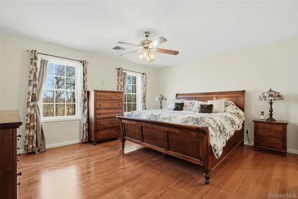 a bedroom with a bed and dresser with wooden floor